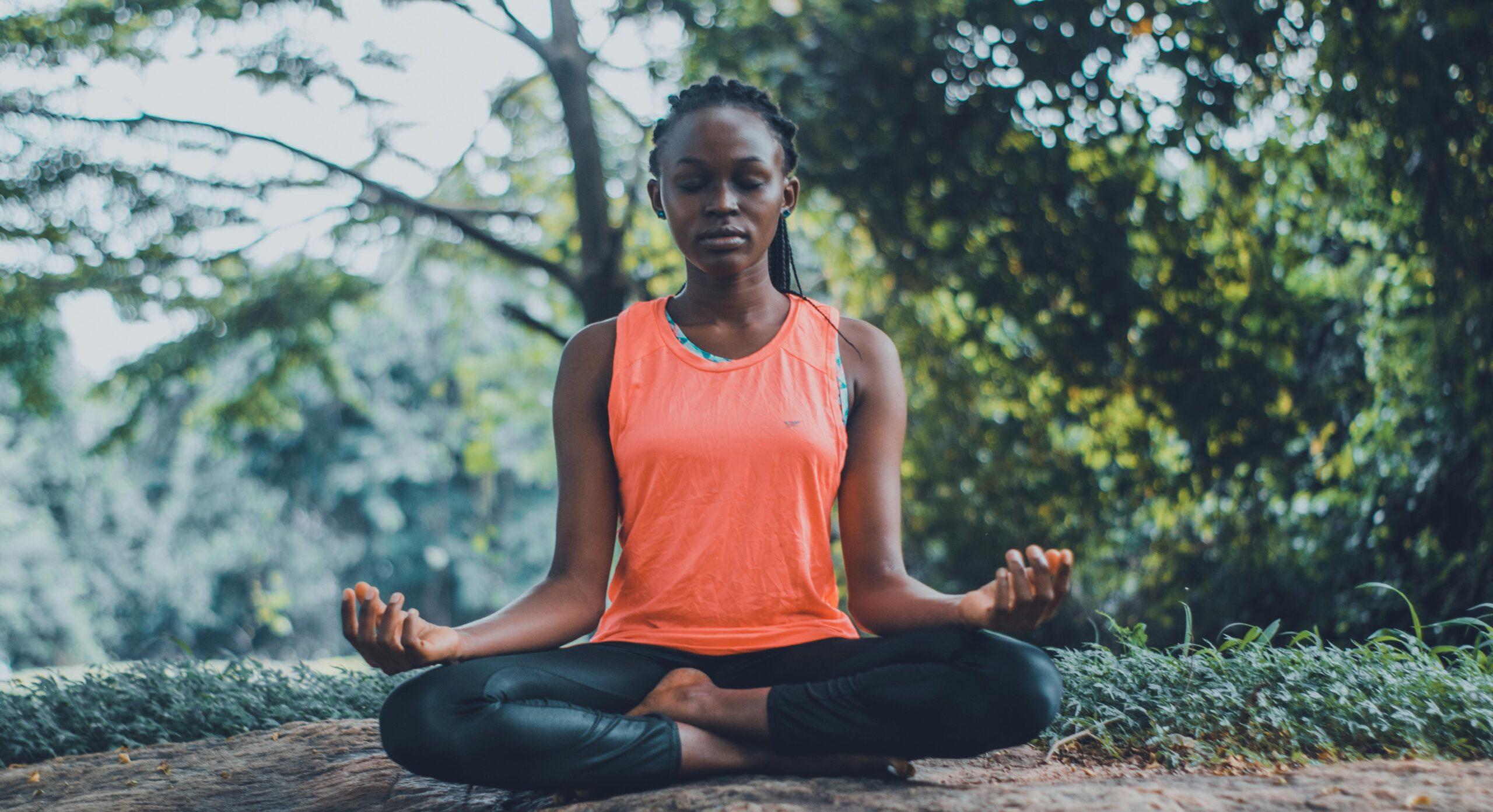 Portrait of a smiling woman meditating outdoors surrounded by fresh flowers