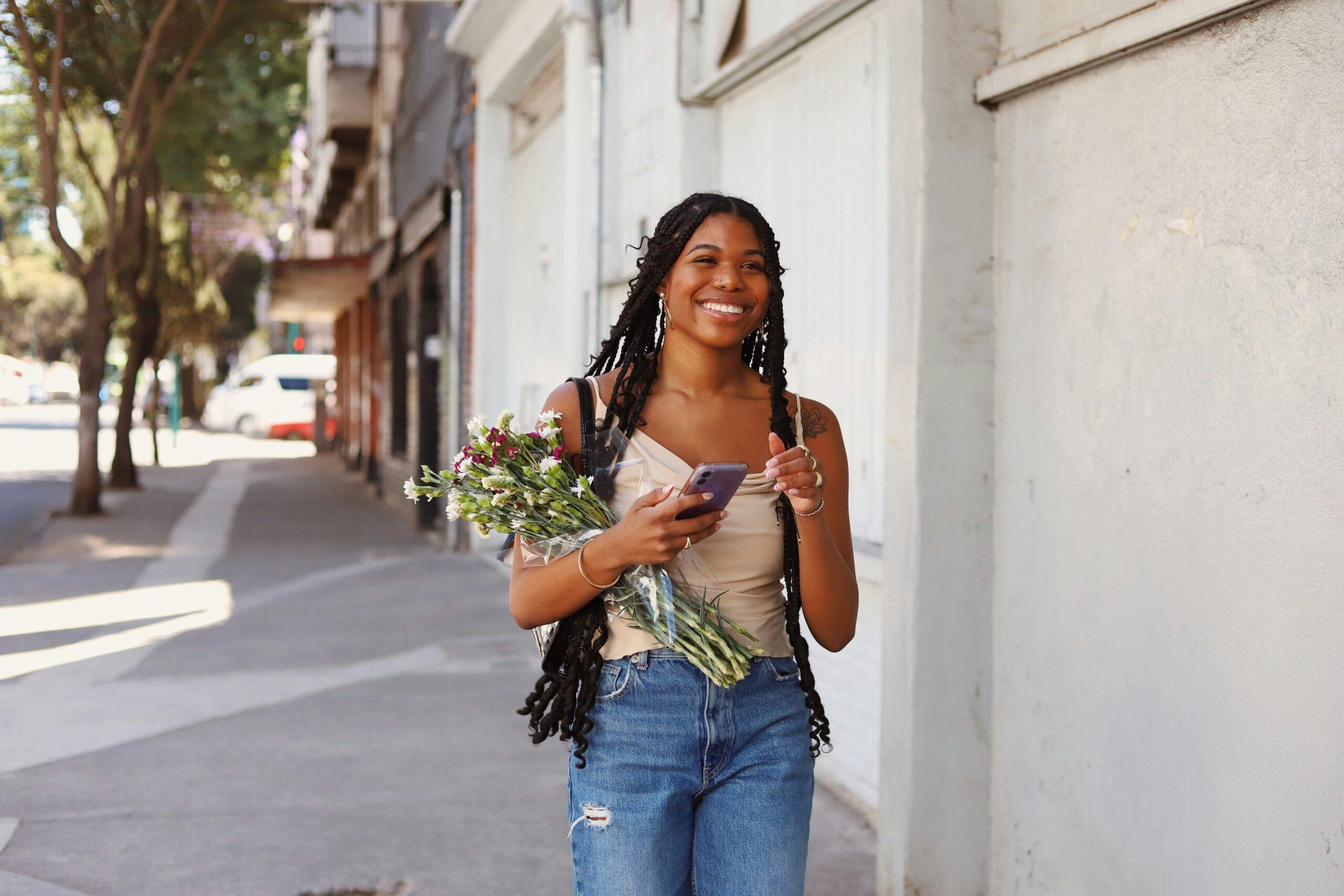 Sarah smiling confidently while holding a small bouquet of fresh spring flowers.