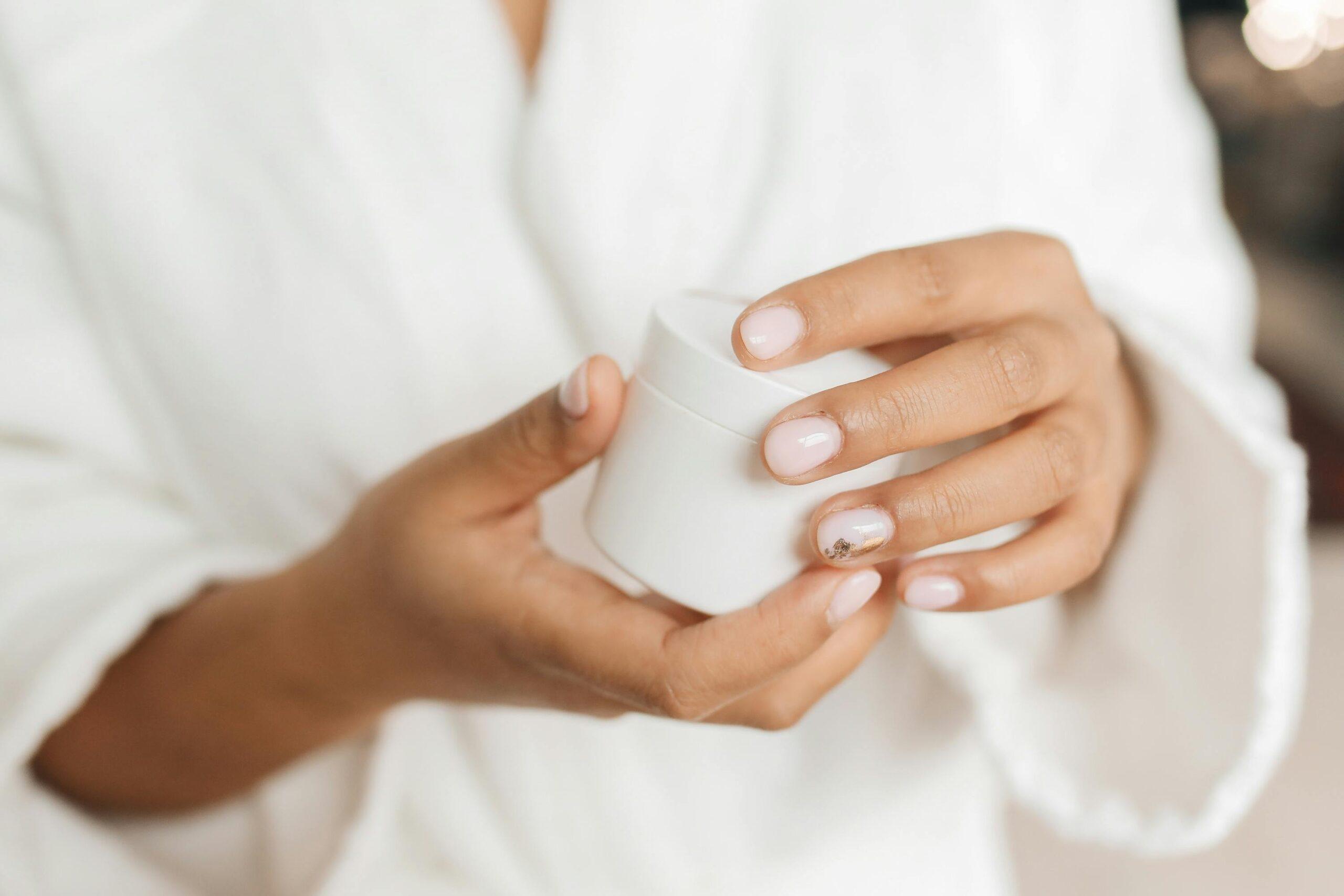 Woman holding jar of organic flower-infused serum with glowing skin