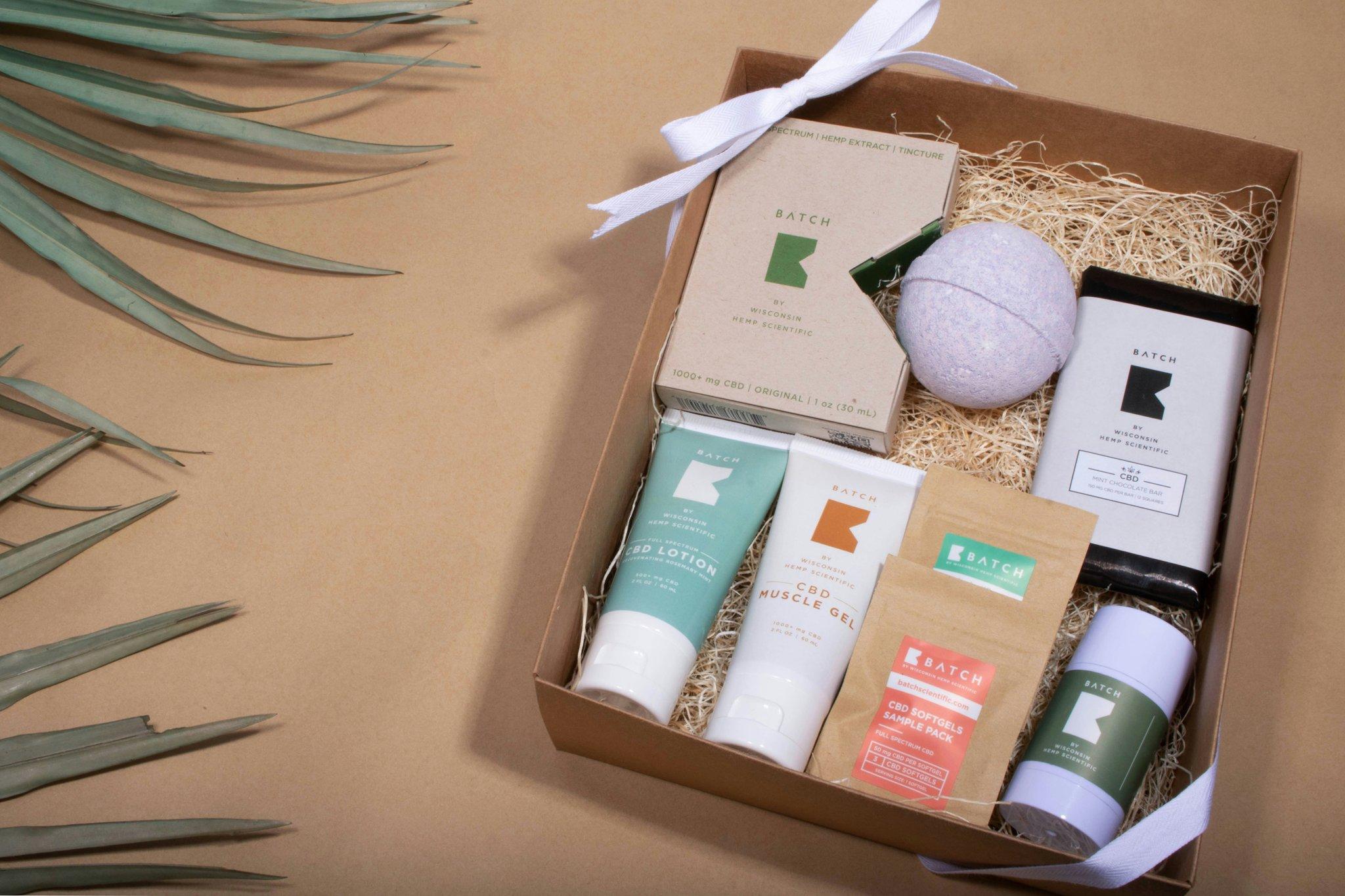 A gift box containing dried flowers, candles, and essential oils