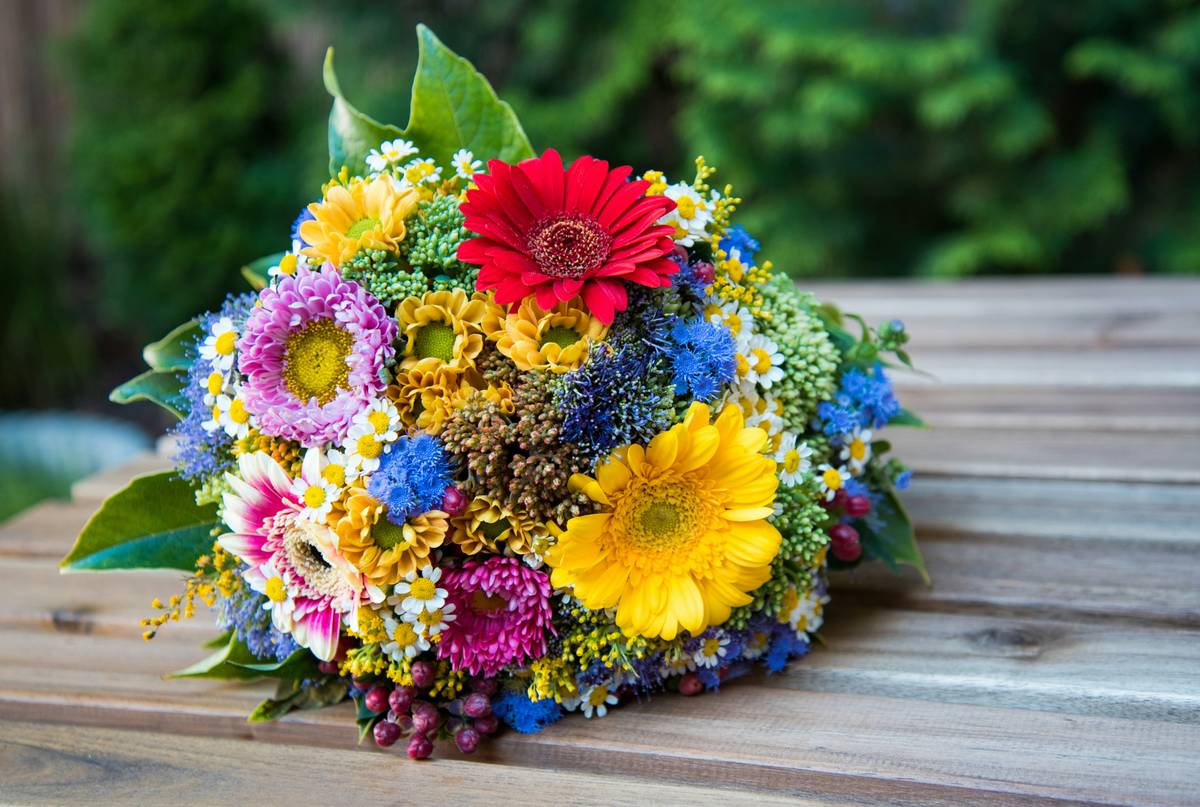 Close-up shot of a balanced floral arrangement featuring white roses, eucalyptus, and berries in a glass vase.